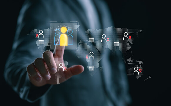 Global workforce management concept. Businessman selects digital user icon on world map interface, symbolizing remote team connection, HR analytics, recruitment, and talent location tracking.