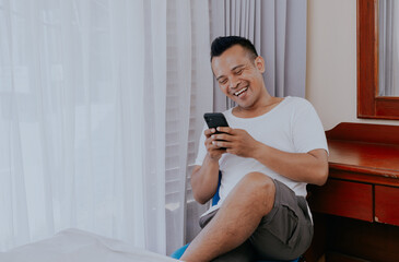Funny laugh face asian man watching funny video clip share in the social media on his smartphone.