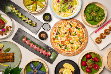 A top view of assorted Asian and Indian dishes—sushi, dim sum, pizza, and mutton seekh...