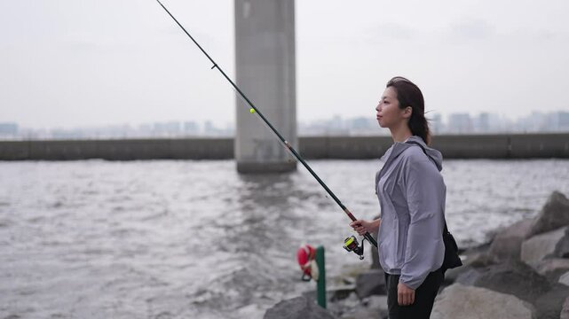 岩場に立ち海を眺める女性の釣り人