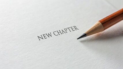 A sharpened pencil rests on a blank page with the words "NEW CHAPTER" typed at the center, symbolizing fresh beginnings.