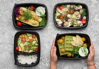 Choosing take away food. Female hands taking container with healthy lunch, top view