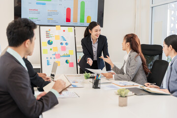 Asian business groups discuss new project documents and make presentations in conference room
