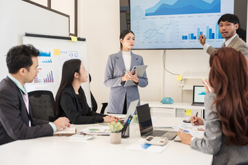 Asian business group discusses new project documents and presents them in the conference room.