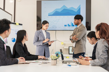Asian business group discusses new project documents and presents them in the conference room.