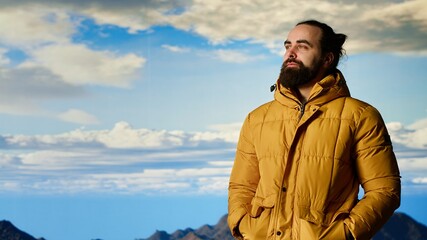 Hiker gazes at the panoramic view of dramatic mountain peaks and clouds, feeling the thrill of adventure and rewards of perseverance. The journey represents strength and personal growth. Camera B.
