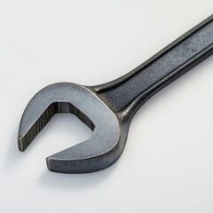 A well-used, dark-grey open-end wrench rests on a plain white background, showcasing its worn texture and slightly dull finish