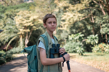 Young boy outdoor hiking backpack and walking stick looks into the distance observing and possibly guide trekking and trail exploration holiday ecotourism concept.