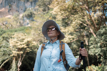 Older trekking adventure carries backpacks poles enjoying nature expression looks into the distance observing and possibly guide trekking and trail ecotourism adventure concept.