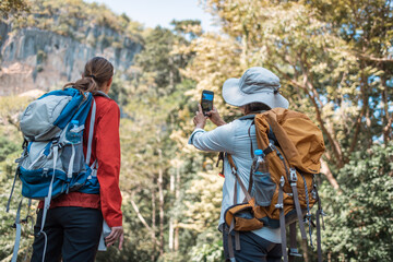 Hikers or explorers family on journey carrying backpack, trekking poles  looks into the distance observing guide trekking and trail exploration holiday ecotourism concept