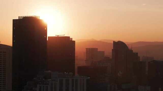 Golden hour aerial view of Ulaanbaatar city skyline in Mongolia with sunset over the mountains and modern high-rise buildings