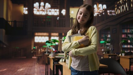 Portrait of cute young schoolgirl entering the library to study in peace, carrying textbooks and learning materials. Preteen scholar preparing for her school lessons, homework session. Camera A.