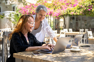 Two Women Collaborating Outdoors on Laptops in Sunny Café Garden, Remote Work Team Concept
