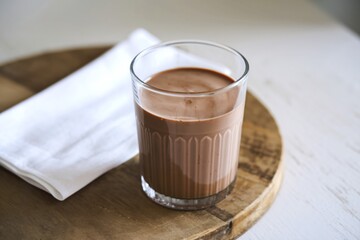 A photo of a clear glass filled with chocolate milk
