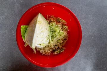 shredded and quarter cabbage in red bowl