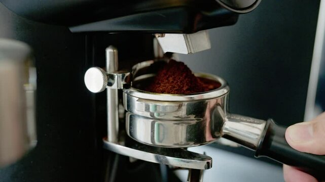 Professional barista worker use grinder machine to grind fresh coffee beans for make hot beverage at coffee cafe shop.