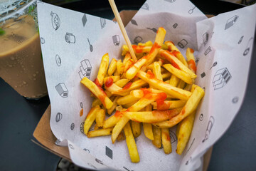 French fries topped with chili sauce served with iced coffee on the table. Light meal or snack at a...