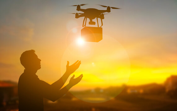 Silhouette of a man Receiving a Delivery from a Drone at Sunset