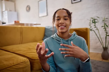 Vitrage gordijnen Happy black teenage girl talking during video call and looking at camera. © Drazen
