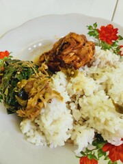 A plate of cooked rice, chicken, and vegetables.