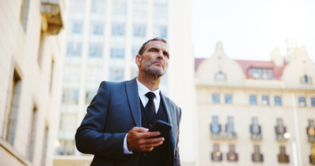 Businessman, phone and waiting in city for taxi, cab ride or transportation to travel. Man, employee or mobile smartphone with app or lift for local commute, destination or location in an urban town © Fanti/peopleimages.com