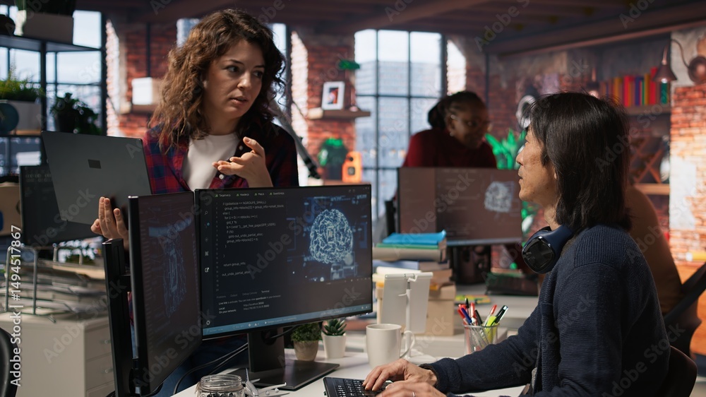 Poster startup intern holding laptop asks questions to senior technician coding advanced ai algorithm. empl
