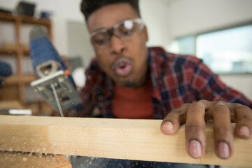 carpenter blowing sawdust from wood