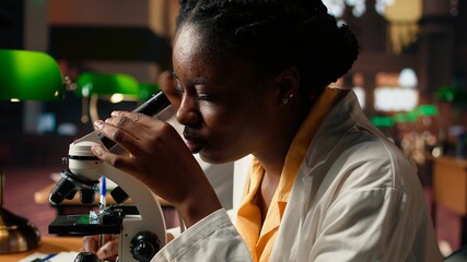 University student prepares for exam by researching cells and microorganisms under the microscope. Using books and papers from the academic database in the college library. Camera A.