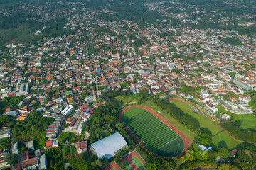Aerial view of a densely populated urban area with a sports complex and lush greenery