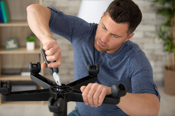 man tightening screw on underside of chair with pliers