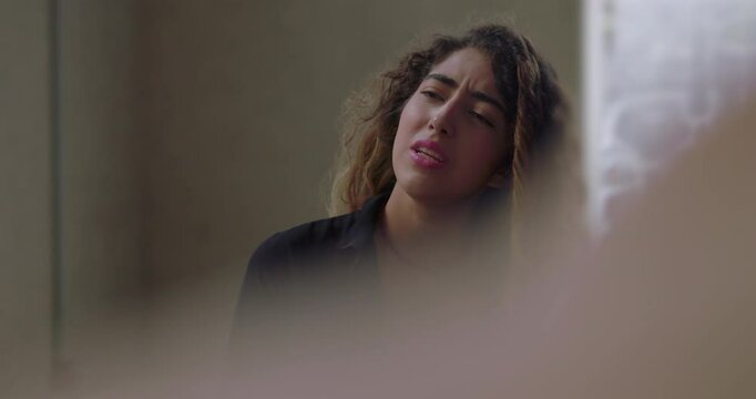 Young woman overwhelmed with emotion while speaking in group therapy, eyes closed as she reveals difficult experience in supportive and nonjudgmental setting