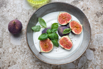 Plate with greek yogurt, fresh fig fruits and basil on a light-brown granite background, horizontal shot, high angle view