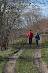 Obraz premium Two boys walking on a path through a park on a sunny day.