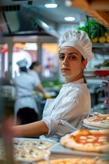 Female chef in a busy kitchen, focusing while preparing pizzas.
