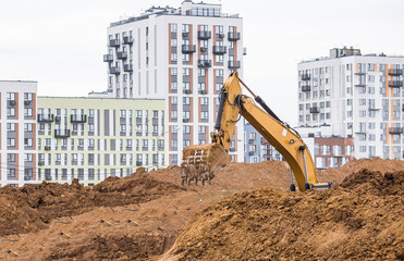 An excavator on a construction site in close-up. An excavator digs the ground with a bucket for...