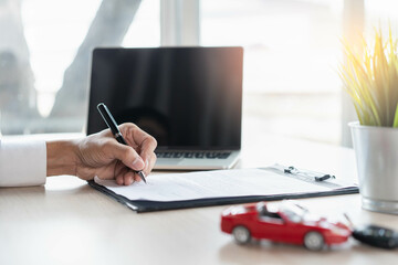 close up shots hands of client signing car lease form.