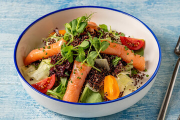 Healthy quinoa salad with smoked salmon, cherry tomatoes, and fresh greens