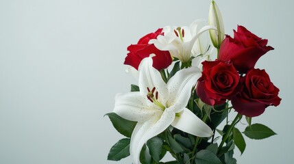 Obraz premium A vibrant bouquet featu red roses and white lilies is beautifully arranged against a soft, neutral background, creating a fresh and elegant floral display.