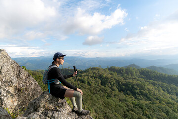 Young man with a backpack enjoying the sunset on the top of the mountain Travel traveler on valley scenery mockup background Mountain climbers watch the sunlight shining on their country journey.