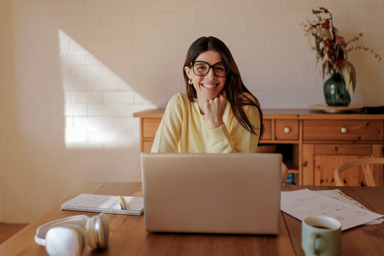 Woman working from home with a laptop and smiling at the camera
