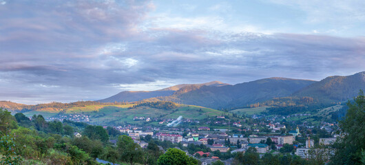 Panoramic view of Volovets town nestled in the Carpathian Mountains, Ukraine. Picturesque sunrise light touches the hills, forests, and charming village landscape.