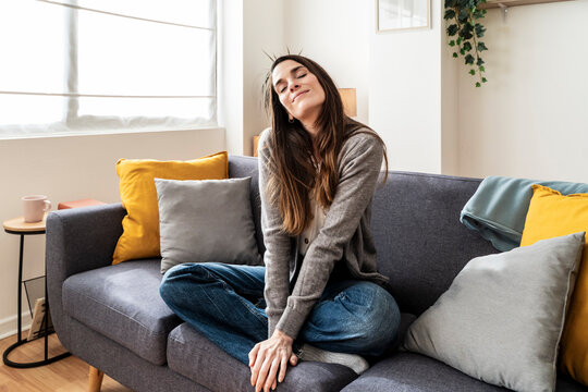 Woman sitting casually on a sofa in a relaxed living room setting