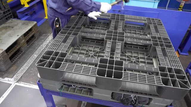 Factory Worker Handling Recycled Plastic Pallets.