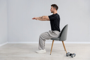 Handsome man exercising with chair at home