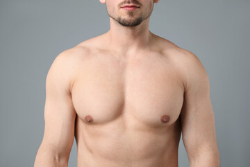 Fototapeta premium Young man with smooth chest after epilation procedure on light grey background, closeup