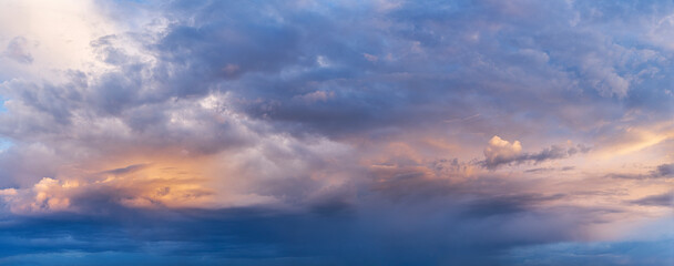 Colorful dramatic clouds during sunset, with layers of light and shadow across the sky. A panoramic view capturing the beauty of changing weather and natural light.