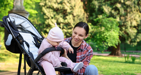 Obraz premium Mother with her cute baby in stroller at park