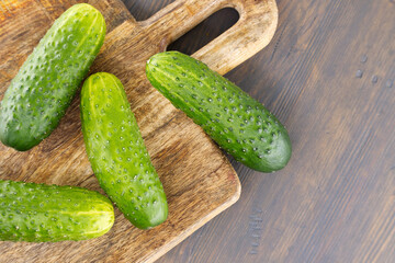 Fresh cucumbers lying on wooden cutting board