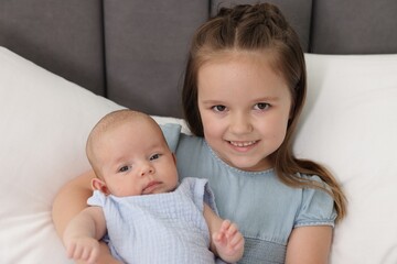 Cute girl and her little sister on bed at home