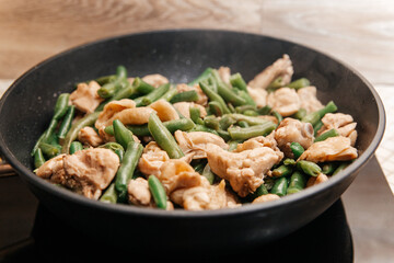 Stewed beans with chicken meat in soy sauce in a frying pan